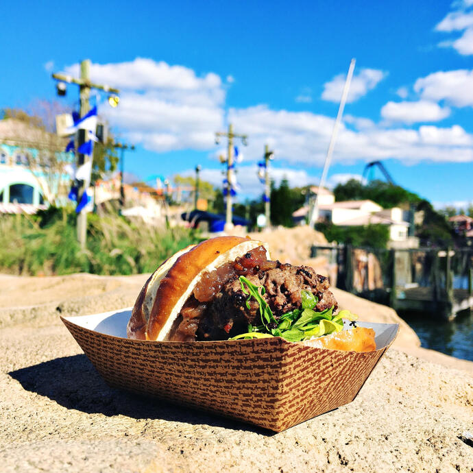 A burger slider in front of a harbor backdrop